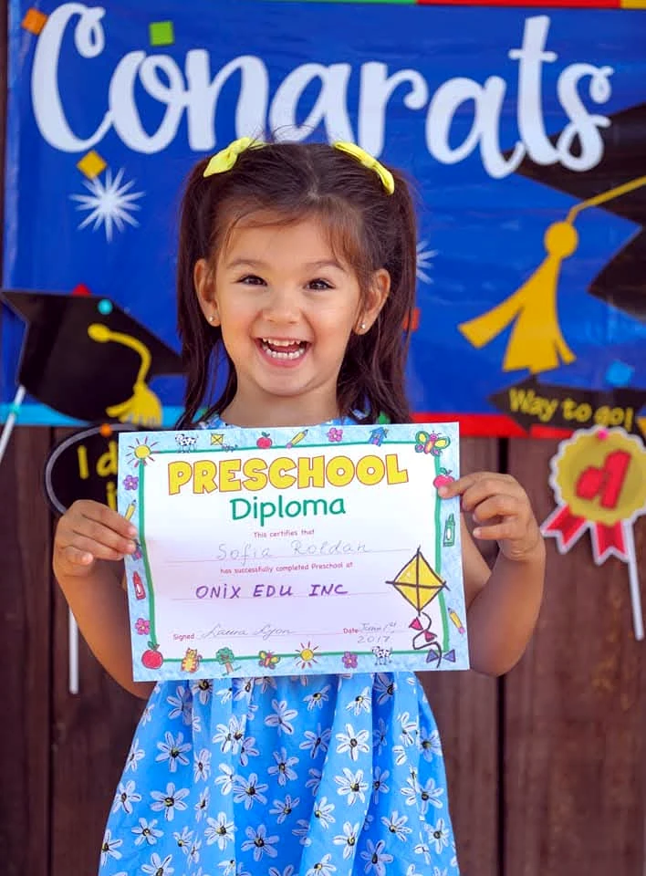 Young child holding an Onix Edu preschool diploma
