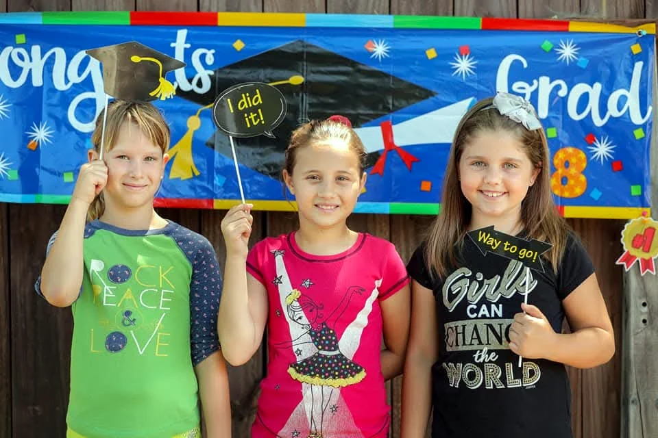 Three young learners celebrating an educational milestone together
